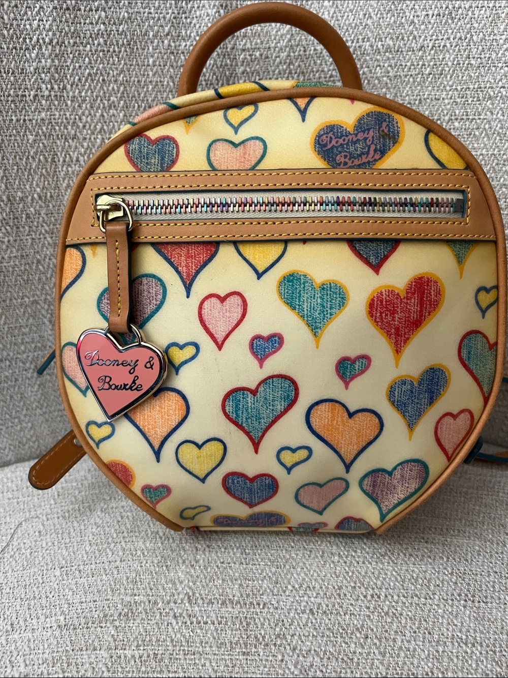 Dooney & Bourke Cream Multi Heart Print Round Backpck with Tan Trim, heart charm